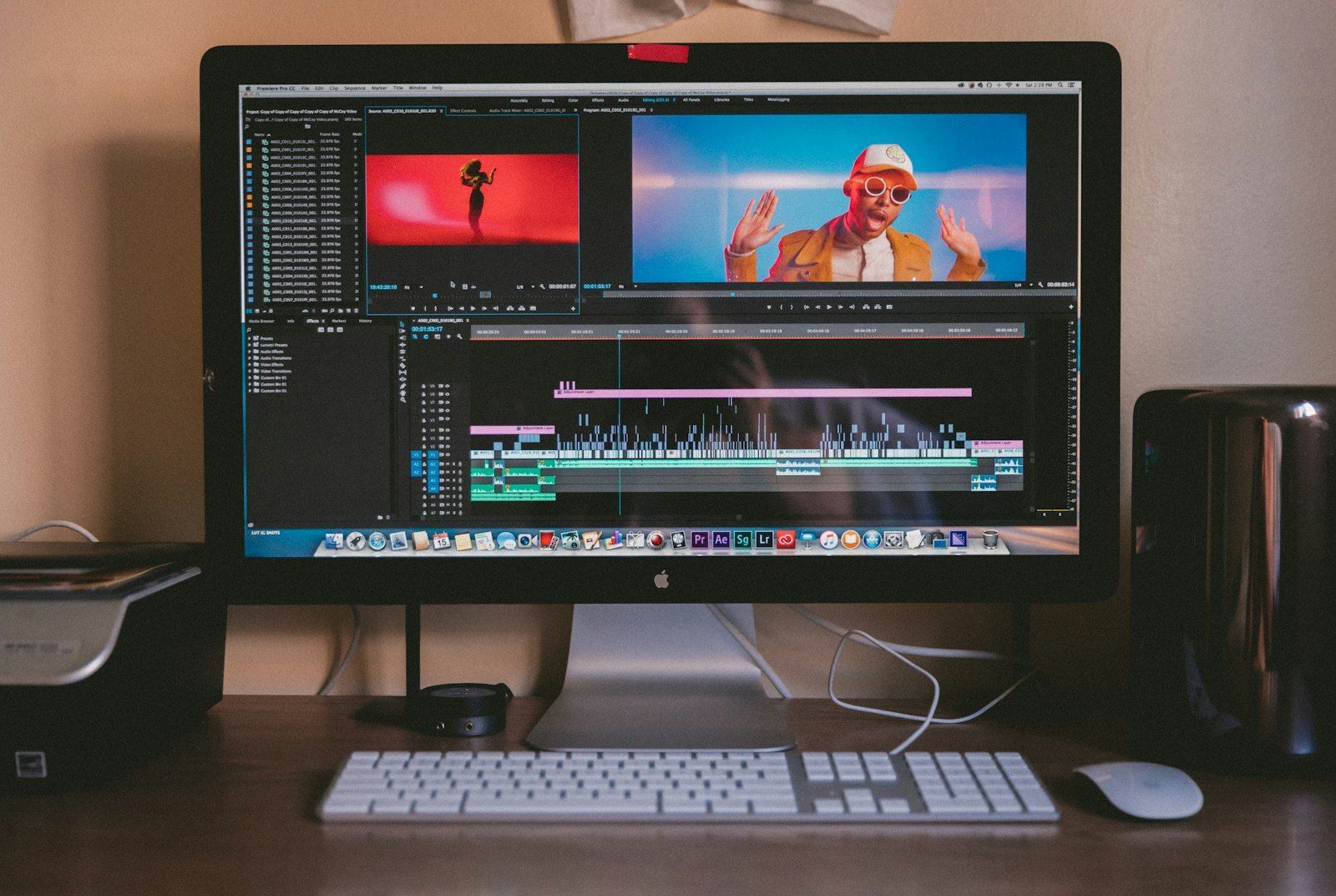 Video editing timeline with audio waveforms on a desktop monitor above a keyboard