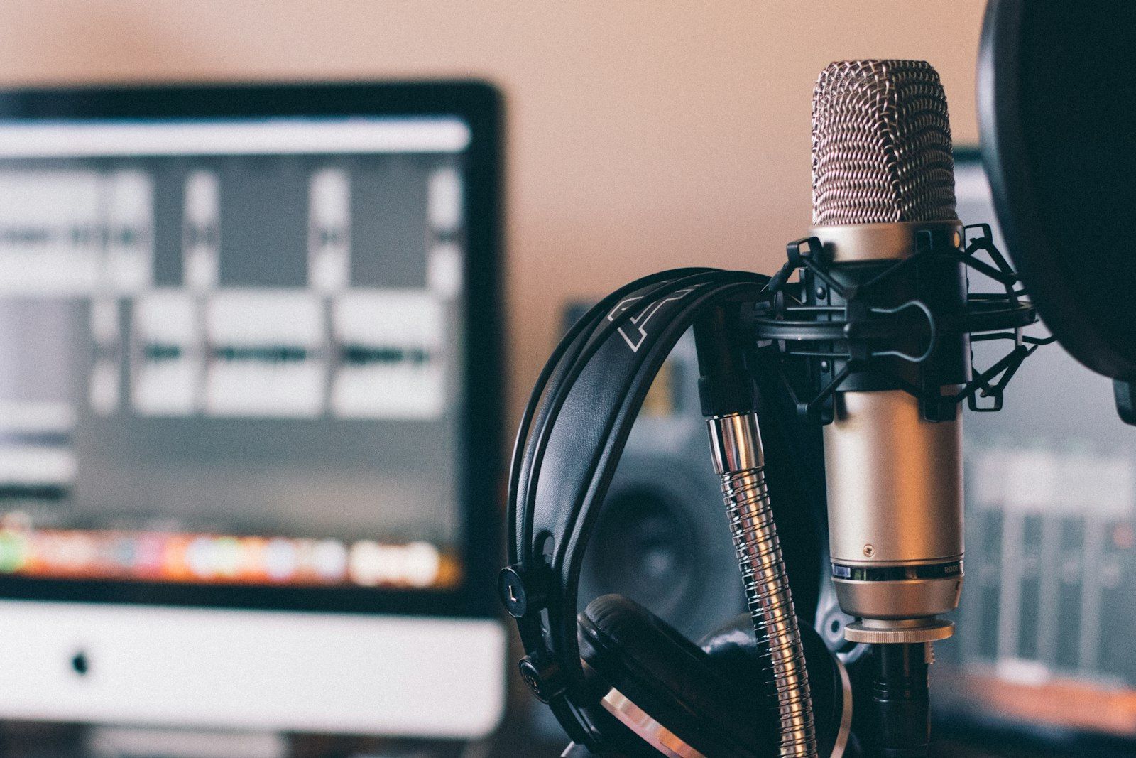 Condenser microphone with headphones in front of a recording software screen