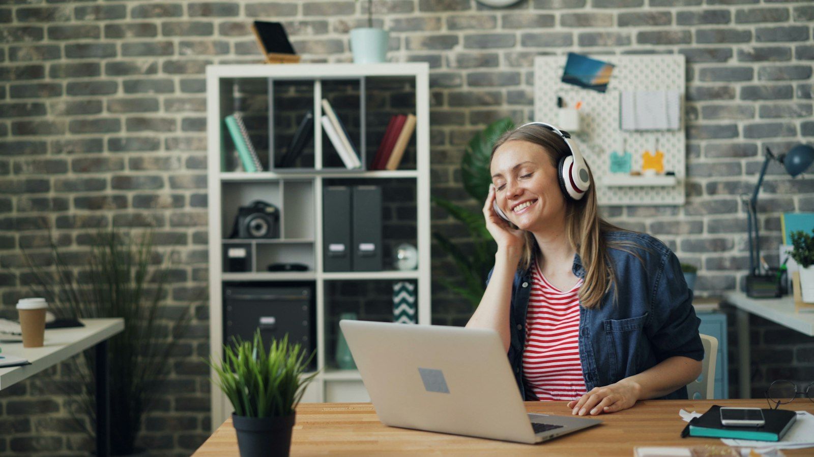 Woman wearing headphones working on a laptop at a desk
