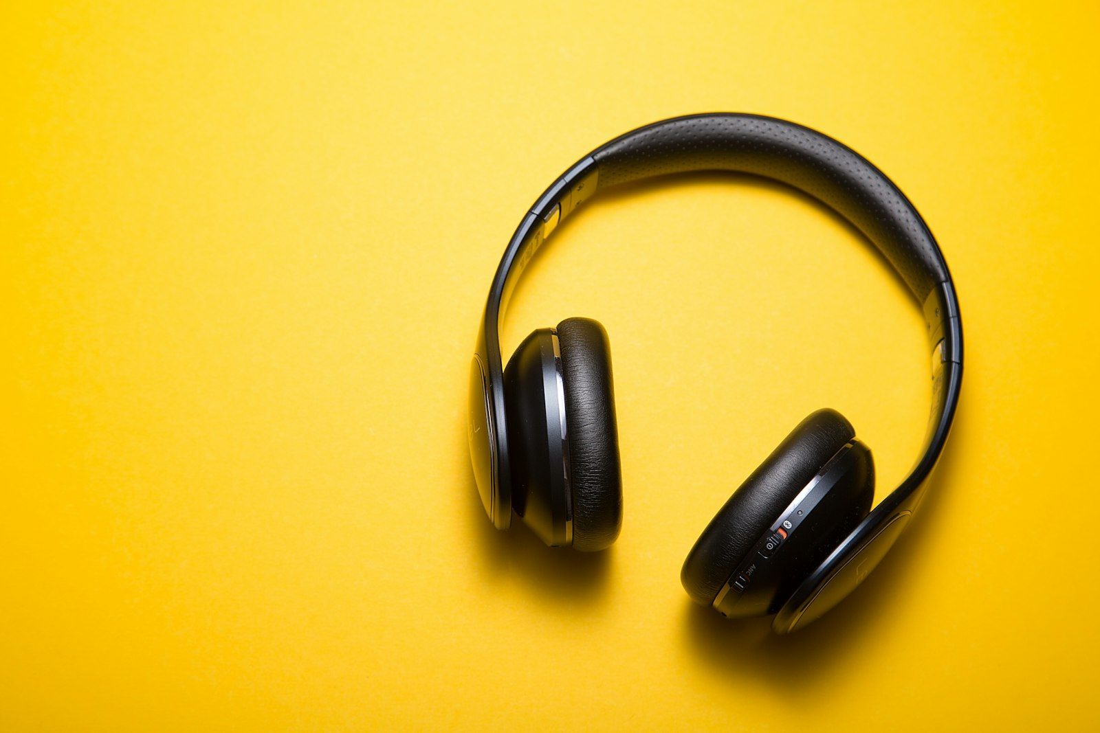 Black over-ear headphones on a bright yellow background