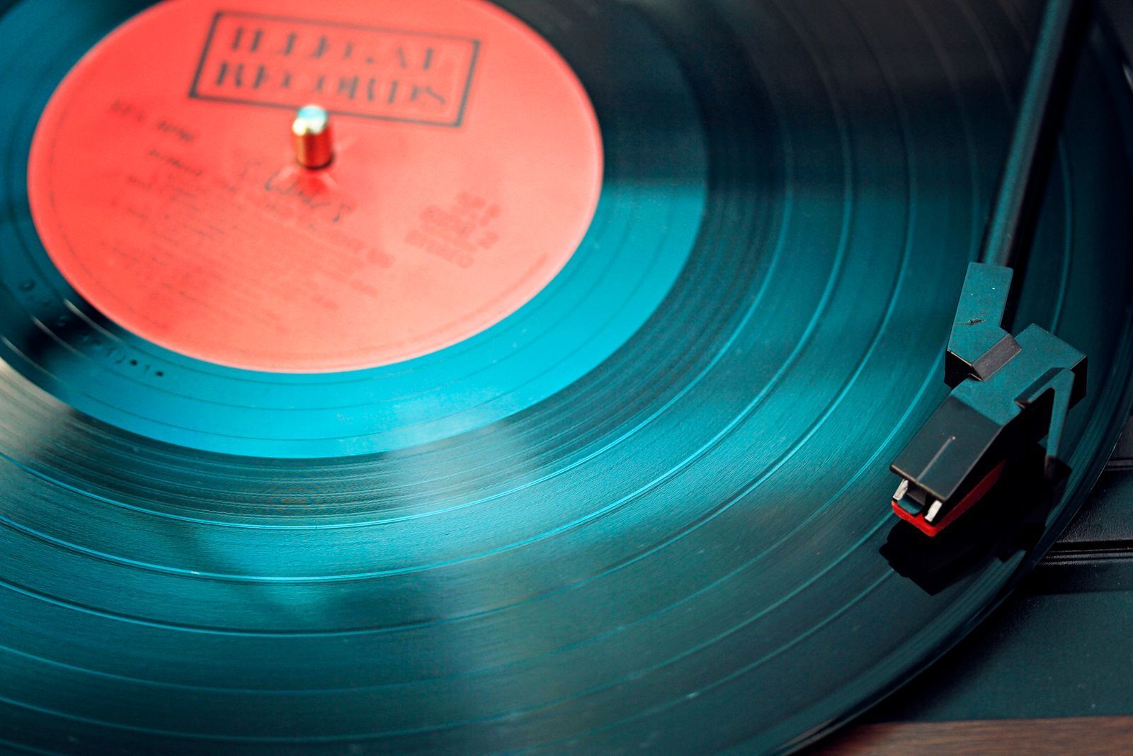 Close-up of a vinyl record with a red label spinning on a turntable with the tonearm resting on it